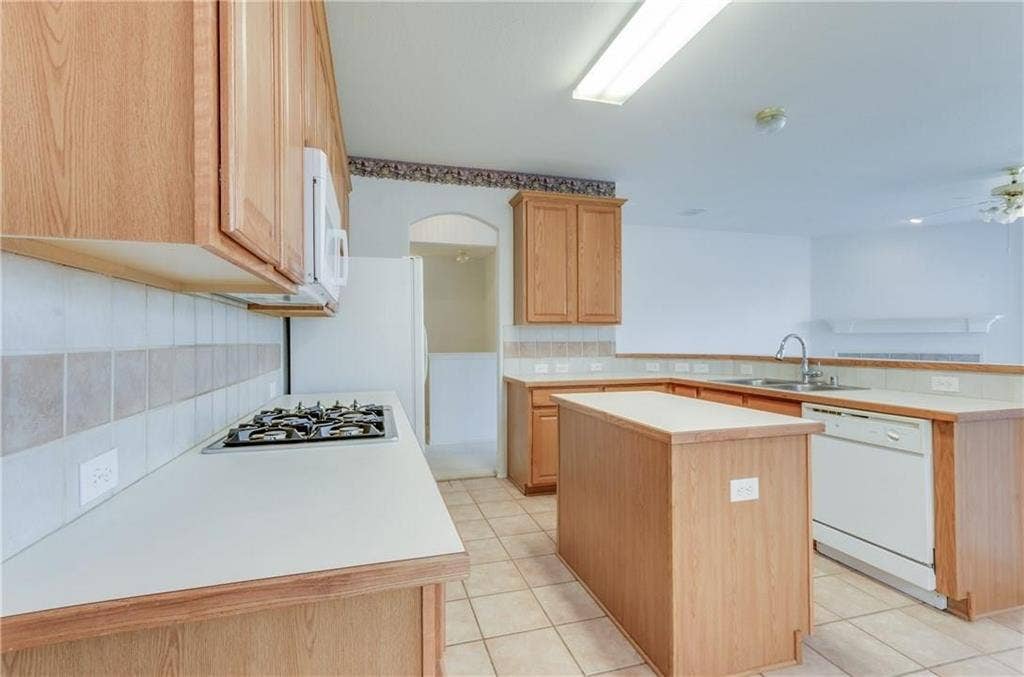 4440 Waskom Drive, Plano, TX 75024 Kitchen featuring a gas cooktop, built-in microwave, tile flooring, wood cabinetry, and a central island