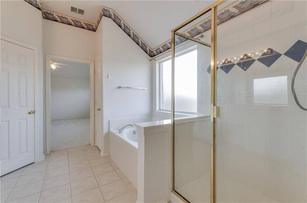 4440 Waskom Drive, Plano, TX 75024 Bathroom featuring a built-in soaking tub, separate shower enclosure with a clear glass door, and a privacy window