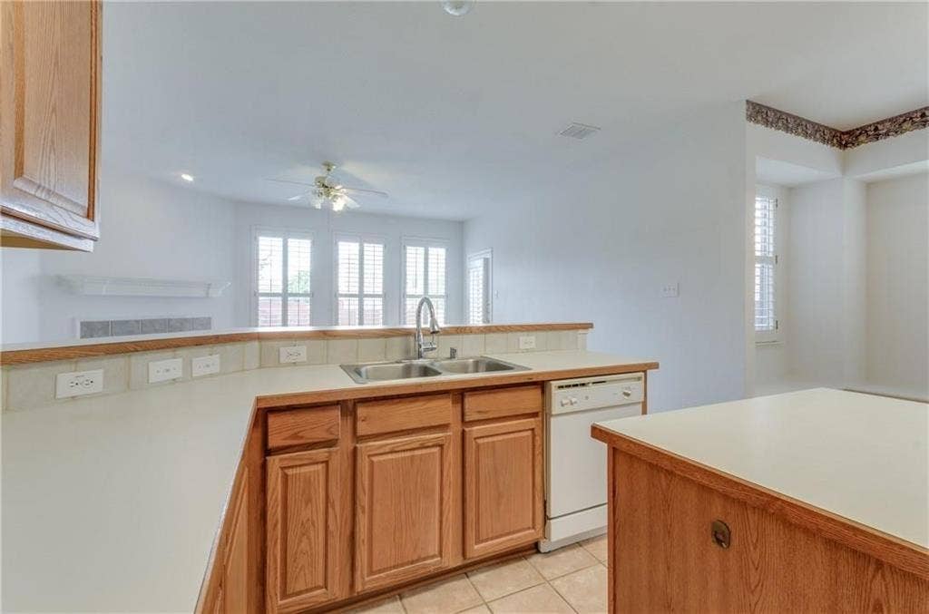 4440 Waskom Drive, Plano, TX 75024 Kitchen featuring wood-finish cabinetry, a built-in dishwasher, and a double basin sink with a high-arc faucet