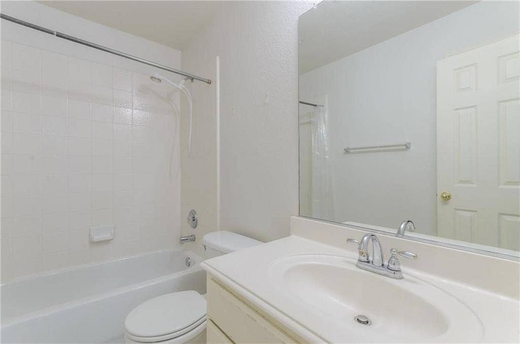 4440 Waskom Drive, Plano, TX 75024 Bathroom featuring a white bathtub with subway tile surround, chrome fixtures, a single-sink vanity with an integrated countertop, and a large mirror