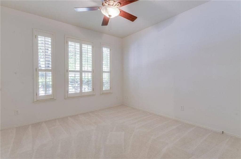 4440 Waskom Drive, Plano, TX 75024 Bright interior room featuring three tall windows with louvered shutters, neutral carpeting, and a ceiling fan with light fixture