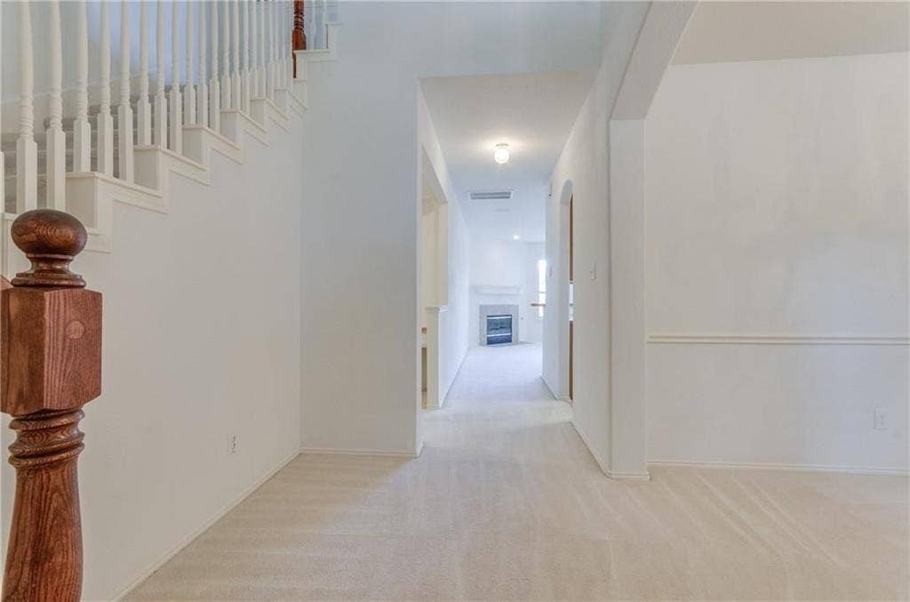 4440 Waskom Drive, Plano, TX 75024 Entryway featuring a wood-finish newel post, white balusters, and a carpeted staircase