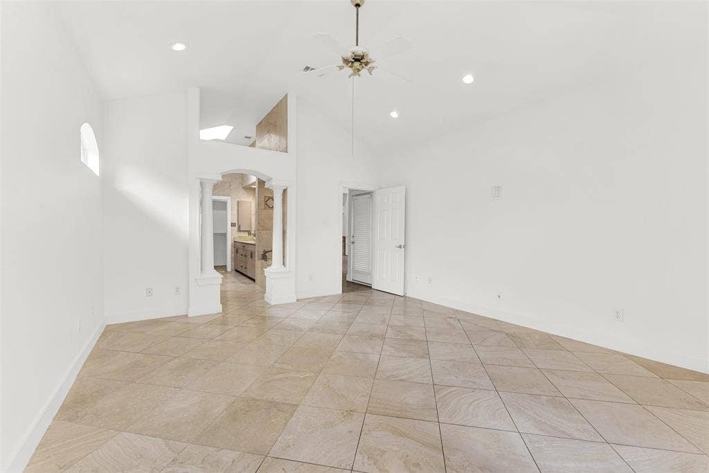 The soaring, multi-faceted vaulted ceiling elevates the room's acoustics and maximizes the sense of openness. Imagine ending your night in this serene, airy sanctuary, watching the shadows soften under the dimmable recessed lighting.