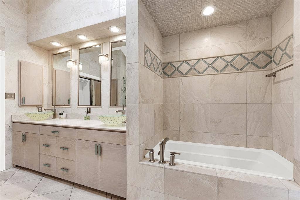 Light wood double vanities stretch beneath glowing, integrated mirrors and translucent vessel sinks. Enjoy an unhurried evening prep routine with plenty of elbow room to wind down comfortably.