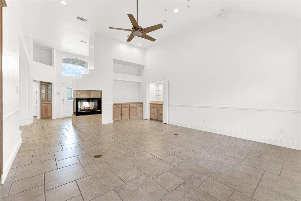The dramatic angled ceiling emphasizes the generous scale and airy feel of this central gathering hall. Picture hosting lively game nights where guests move freely between the warmth of the hearth and the adjacent serving station and classic wet bar.