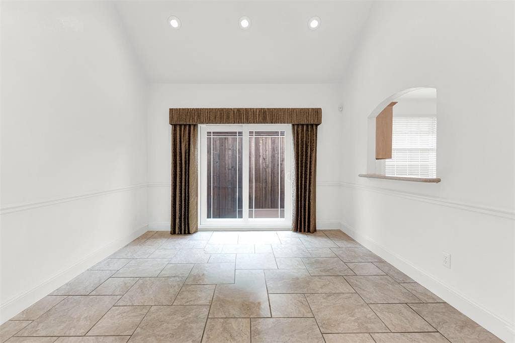 Soaring vaulted ceilings paired with floor-to-ceiling sliding glass doors create a bright, airy sanctuary. Visualize sitting down to a peaceful weekend breakfast illuminated by soft natural light