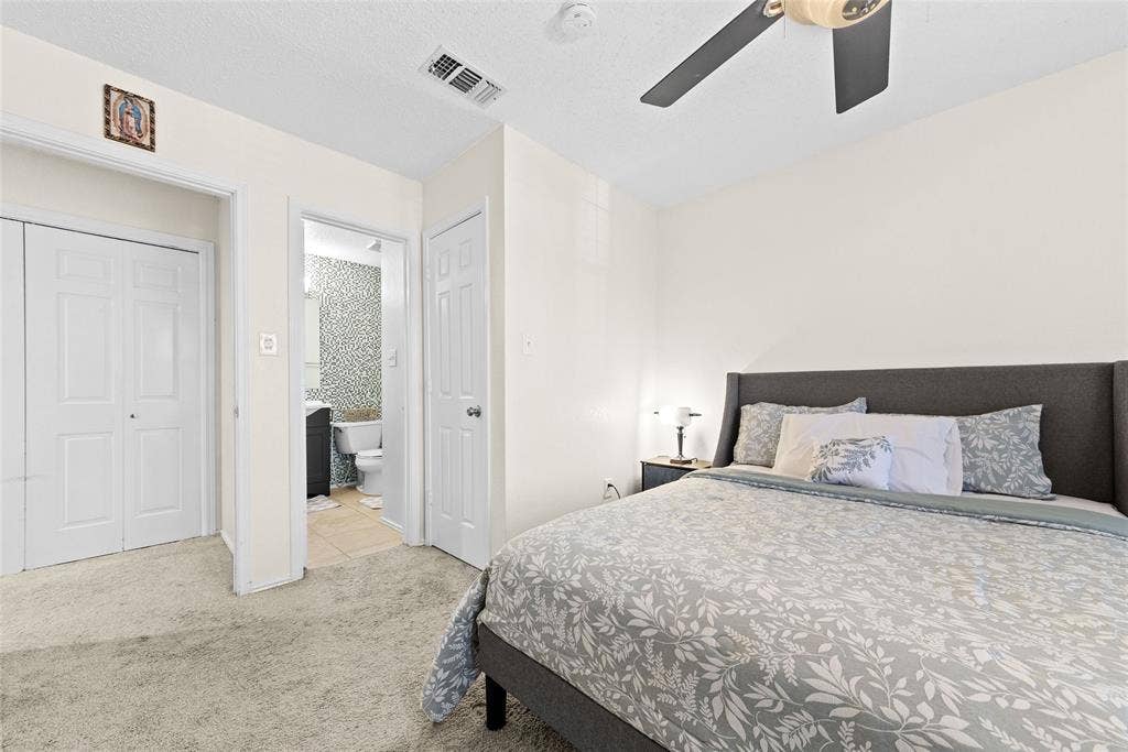 Carpeted bedroom with a ceiling fan, white walls, and bi-fold closet doors