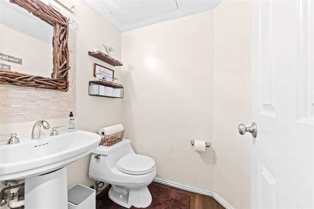 Pedestal sink with chrome faucet, complemented by a decorative mirror featuring a natural branch frame