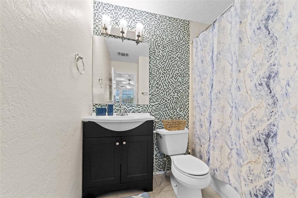 Bathroom featuring a dark wood vanity with white countertop, integrated sink, and an overhead three-bulb light fixture