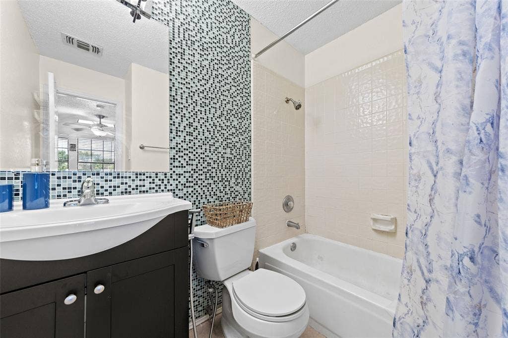 Bathroom featuring a tile accent wall, vanity with an integrated sink, and a built-in bathtub with shower
