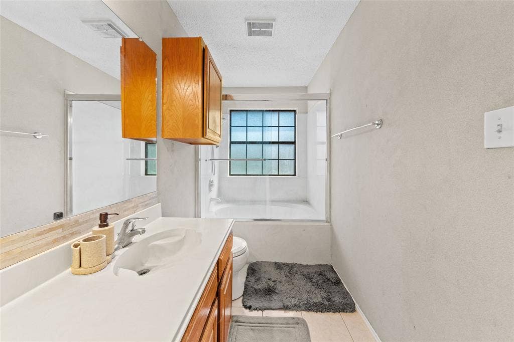 Bathroom featuring a vanity with a white countertop, wood-finish cabinetry, and an integrated sink basin