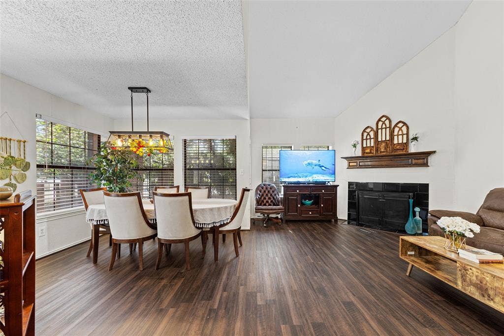 Spacious living area featuring wood-finish flooring, a decorative fireplace with a dark tile surround, and an integrated mantel