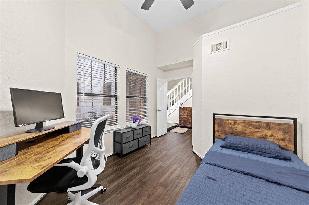 Interior space featuring vaulted ceilings, wood-finish flooring, and multiple windows with blinds