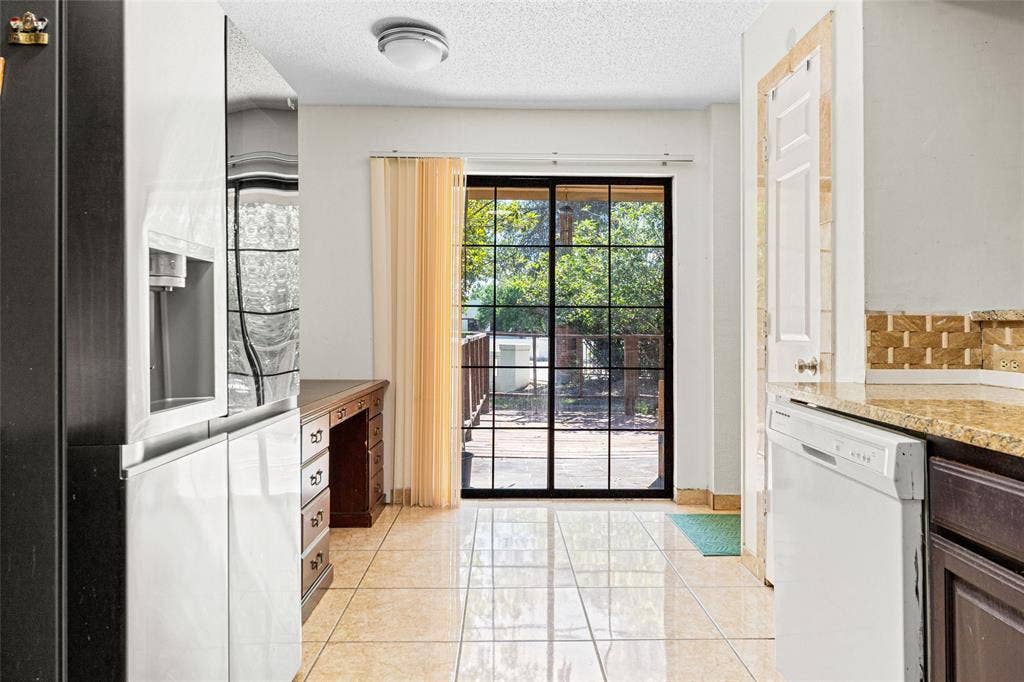 Kitchen featuring granite countertops, wood-finish cabinetry, a stainless steel sink with a black gooseneck faucet, and a patterned tile backsplash
