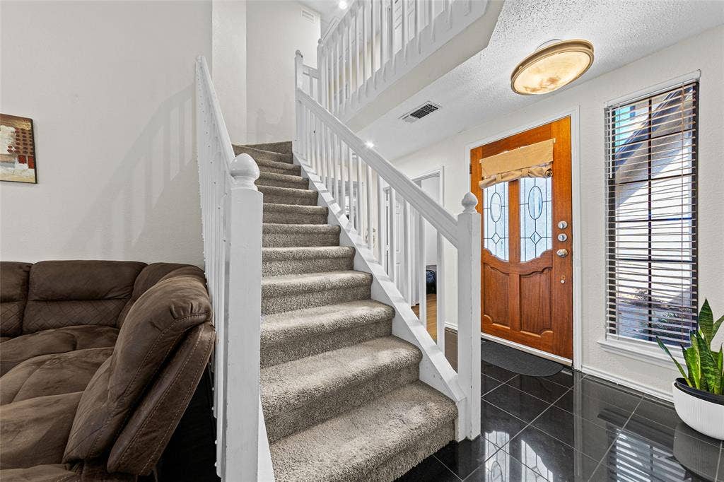 Staircase with white wood railings and carpeted treads
