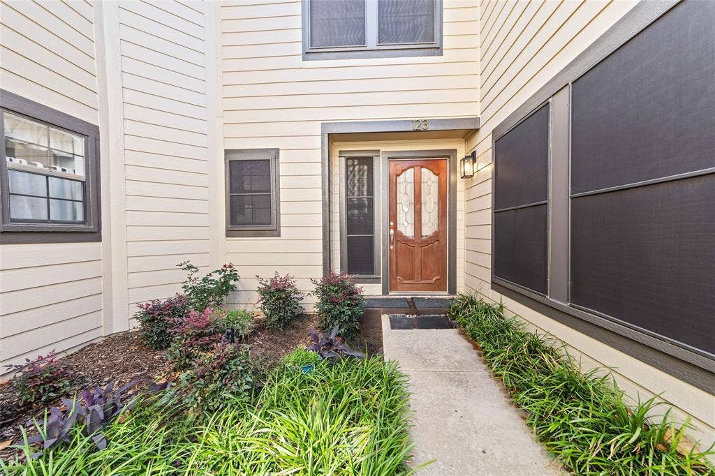 Front entry featuring a wood door with decorative glass inserts, an overhead light fixture, and a concrete walkway