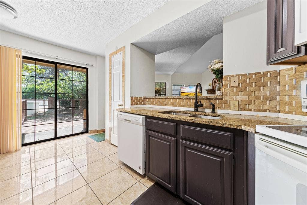 Kitchen featuring plum-finish cabinetry, granite-style countertops, mosaic tile backsplash, and tile flooring