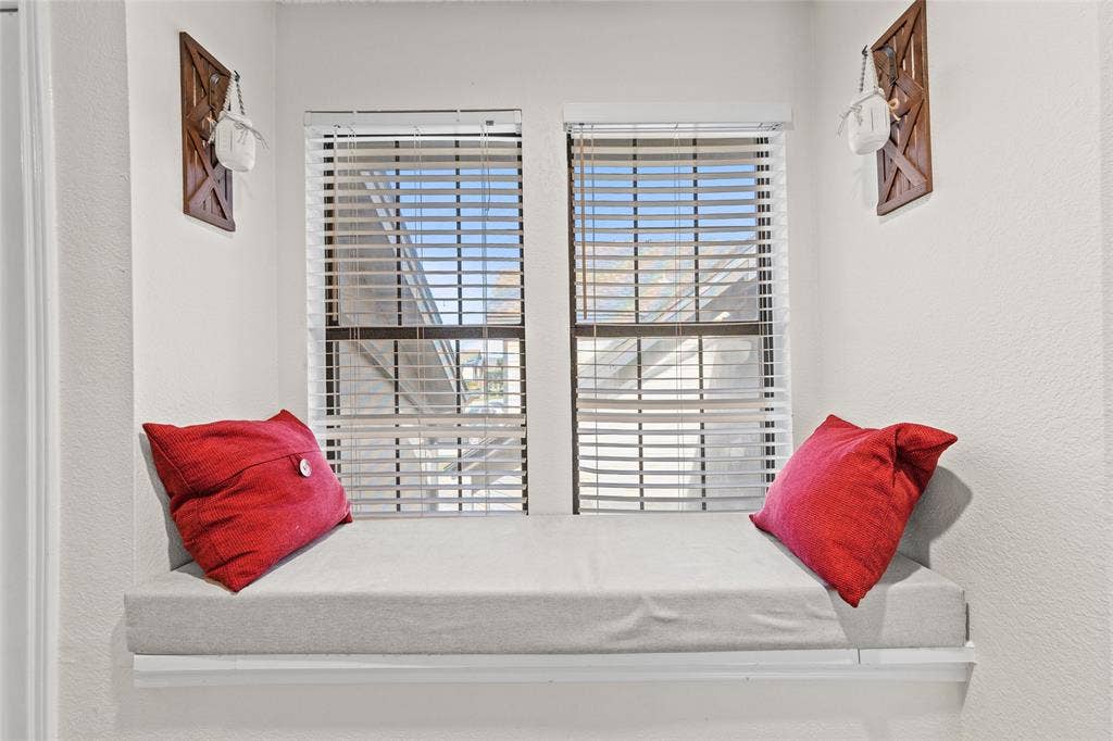 Built-in window seat with a neutral-toned cushion, two double-hung windows, and horizontal blinds