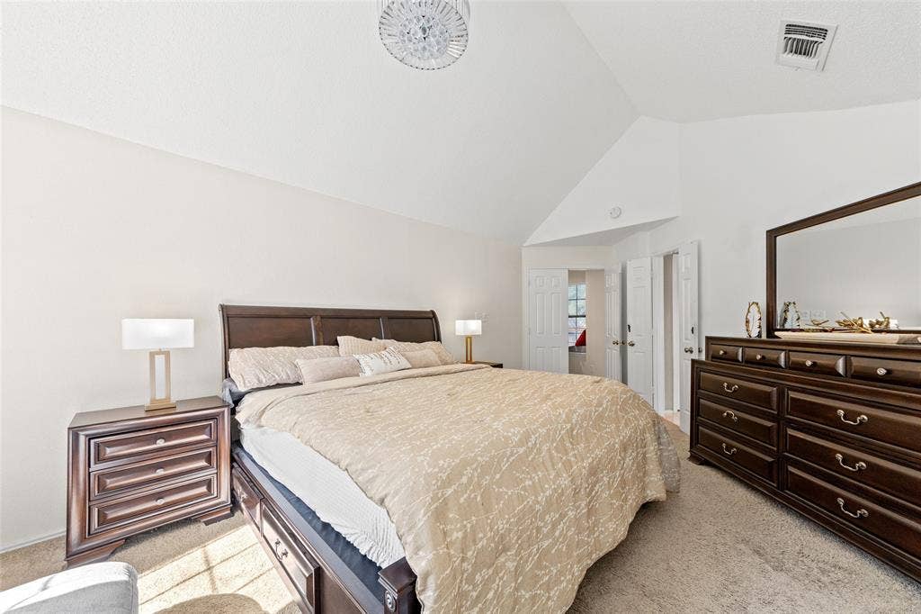 Room featuring vaulted ceilings, light-colored carpet flooring, and a crystal-style flush mount ceiling light