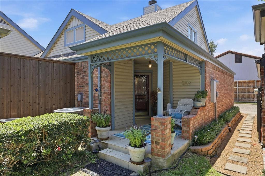 Covered front porch entry with decorative lattice trim, brick pillars, and tiled steps