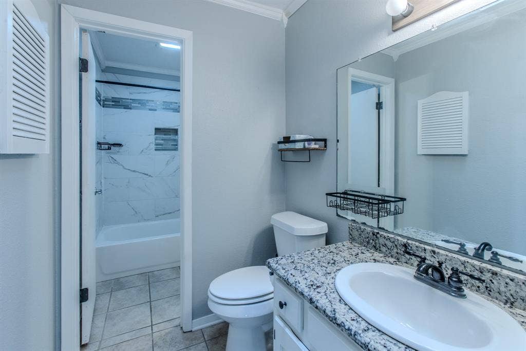 Bathroom featuring a vanity with a white oval sink, speckled countertop, and dark-finished faucet