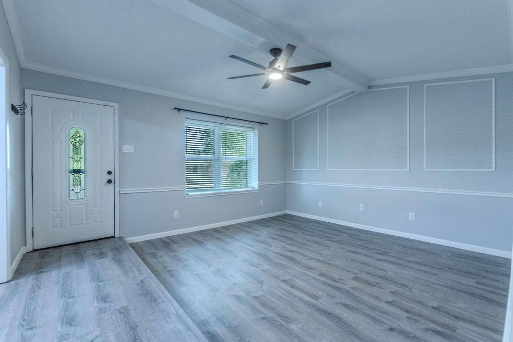 Spacious interior featuring wood-finish flooring, a decorative entry door with leaded glass, and a modern ceiling fan