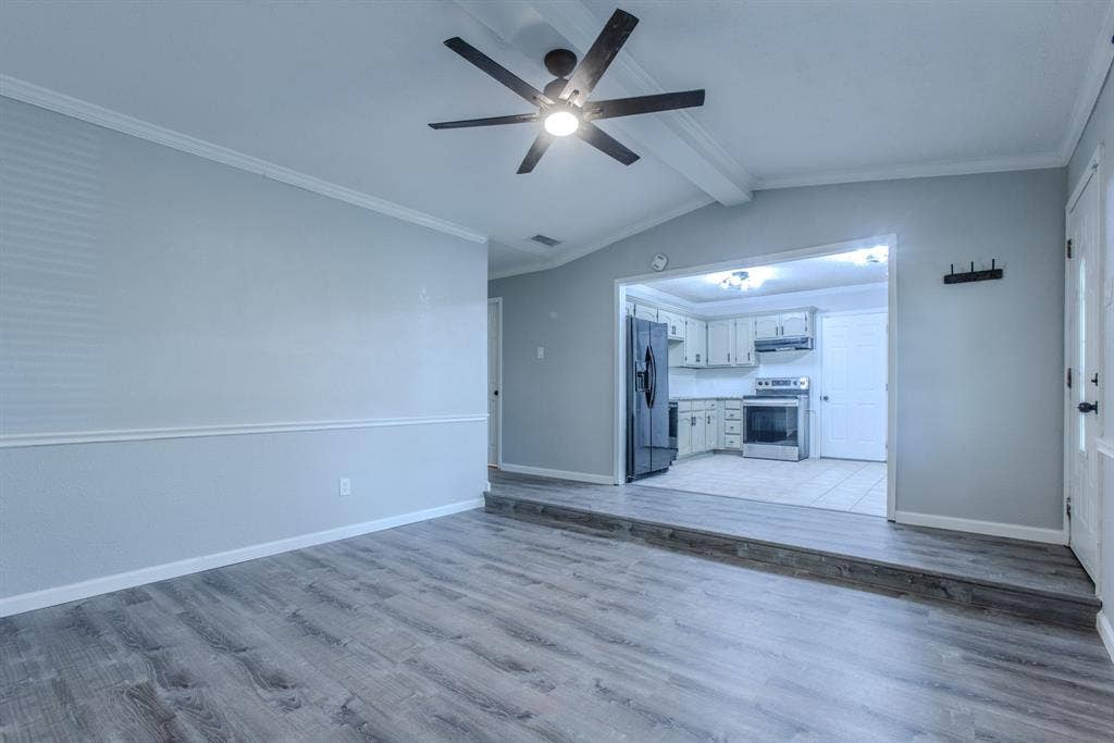 Spacious living area featuring wood-finish flooring, crown molding, and a ceiling fan