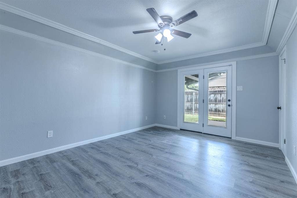 Room featuring wood-finish flooring, crown molding, and a ceiling fan