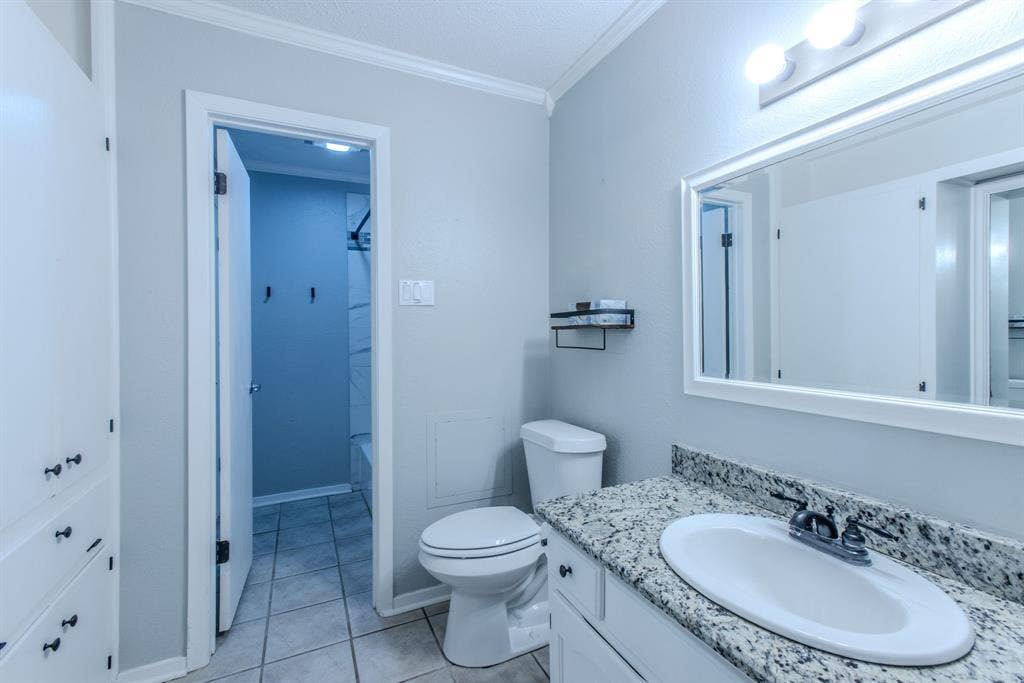 Bathroom featuring a white vanity with granite-finish countertop, undermount sink, and framed mirror