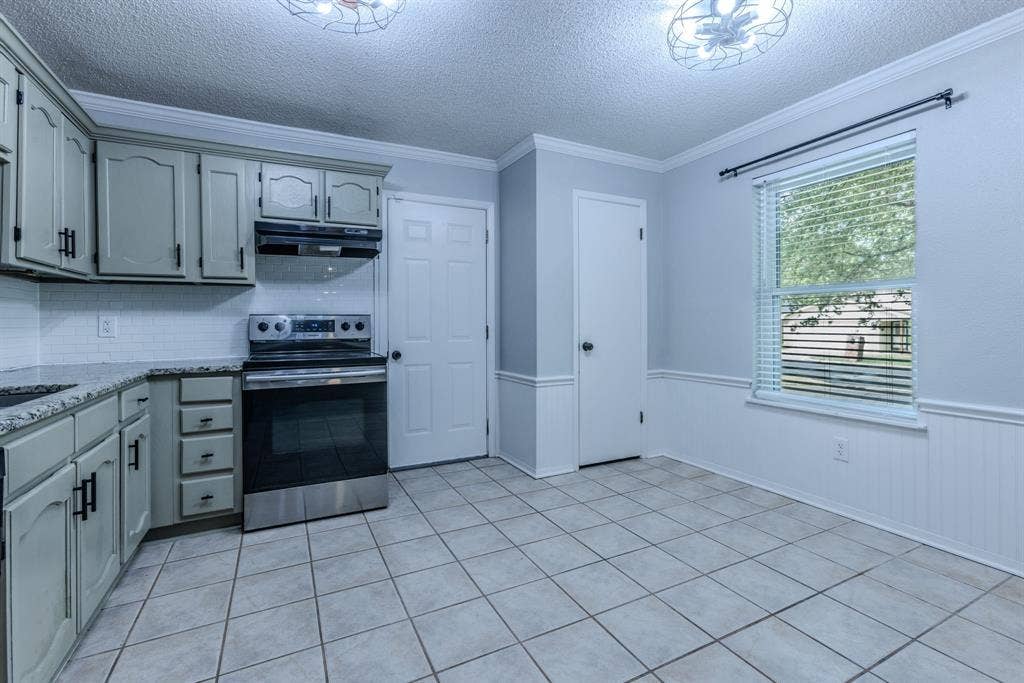 Kitchen featuring light-toned cabinetry, granite-style countertops, a tile backsplash, and stainless steel appliances
