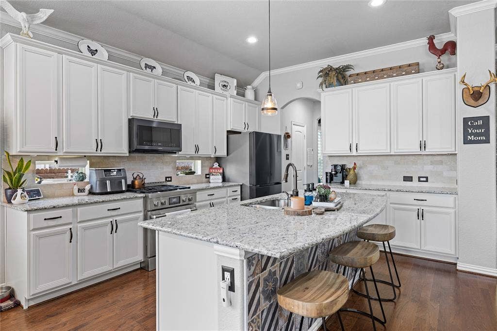 12012 Tobosa Circle, McKinney, TX 75071 Kitchen with decorative light fixtures, crown molding, stainless steel appliances, and dark wood-type flooring