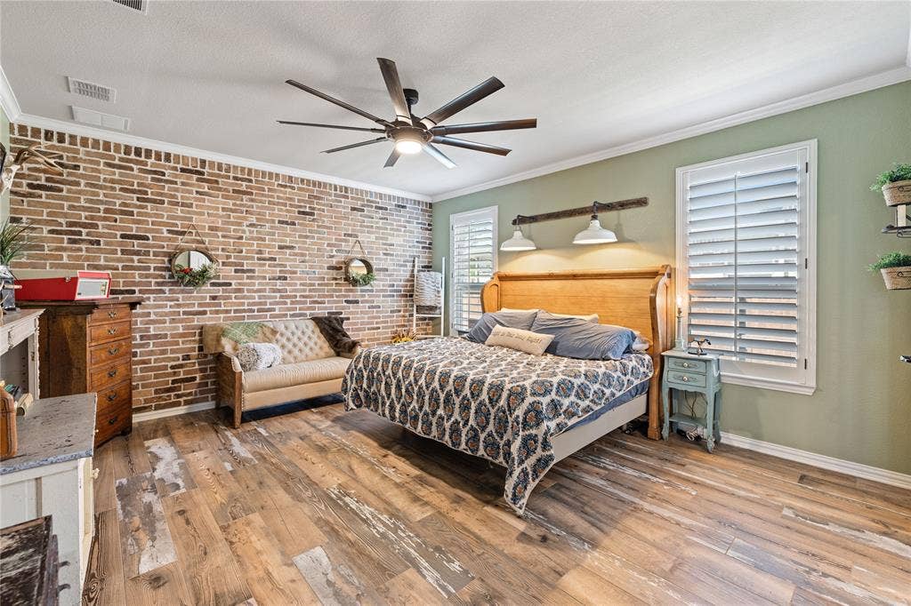12012 Tobosa Circle, McKinney, TX 75071 Bedroom with ceiling fan, crown molding, brick wall, a textured ceiling, and light wood-type flooring