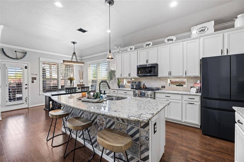 12012 Tobosa Circle, McKinney, TX 75071 Kitchen with a healthy amount of sunlight, pendant lighting, stainless steel appliances, and dark hardwood / wood-style floors