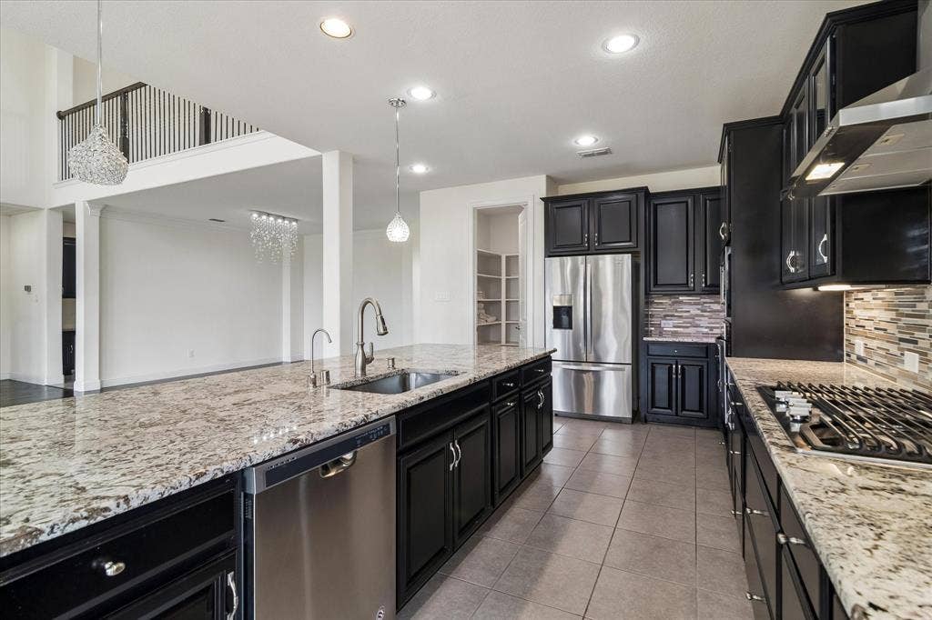 1650 Chisholm Trail, Prosper, TX 75078 Gourmet kitchen featuring granite countertops, dark cabinetry, stainless steel appliances, a gas range, and a breakfast bar island with an undermount sink