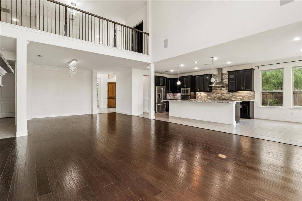 1650 Chisholm Trail, Prosper, TX 75078 Spacious open-concept interior featuring high ceilings, dark wood-finish flooring, and a modern kitchen with dark cabinetry