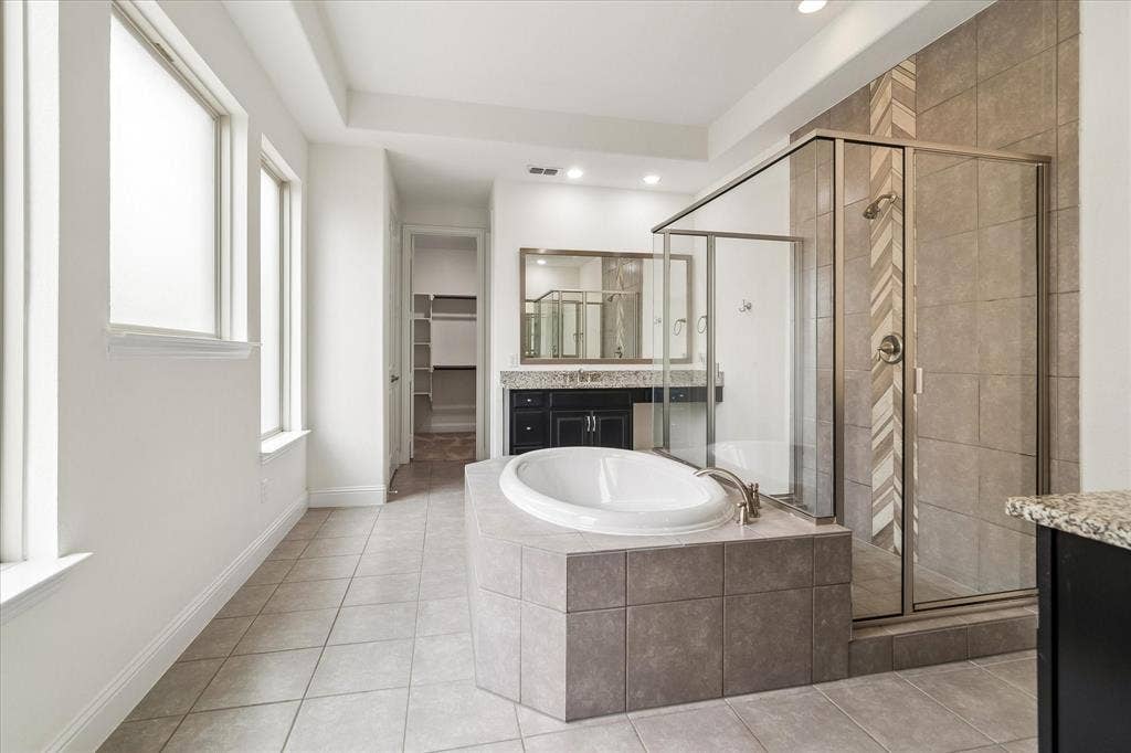 1650 Chisholm Trail, Prosper, TX 75078 Spacious bathroom (19X 11) featuring a built-in soaking tub with tiled surround, a glass-enclosed shower with a decorative tile accent, dual windows, and tile flooring