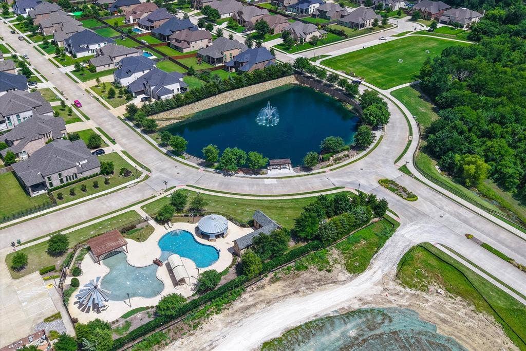 1650 Chisholm Trail, Prosper, TX 75078 Community pool - Aerial perspective showcasing a residential community with a central pond featuring a fountain