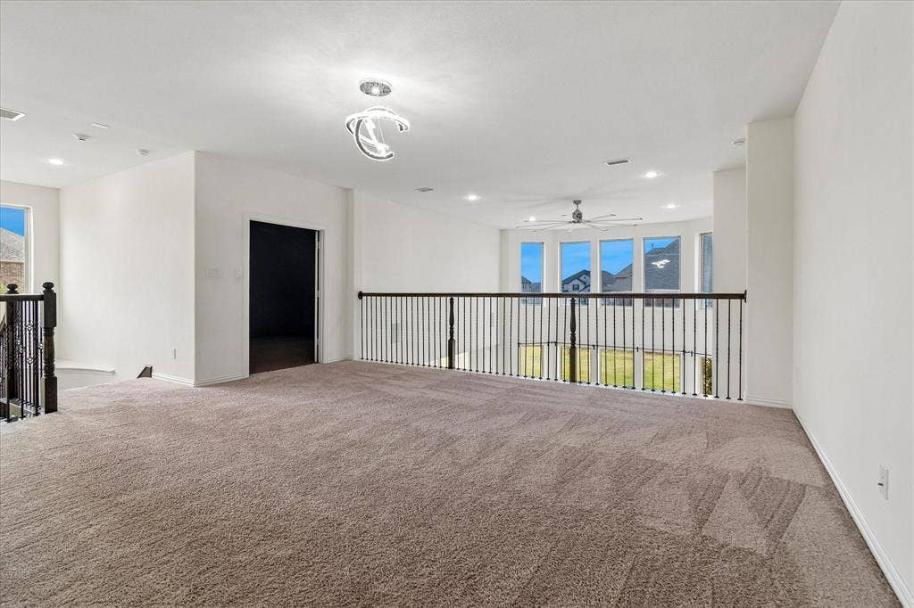 1650 Chisholm Trail, Prosper, TX 75078 Spacious carpeted bonus room featuring a contemporary ceiling light fixture, recessed lighting, and a dark iron railing