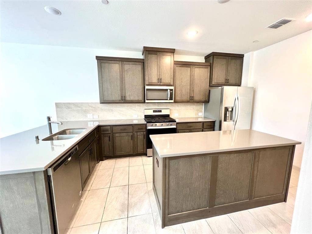 1755 Montgomery Drive, Plano, TX 75075 Kitchen featuring a center island, appliances with stainless steel finishes, tasteful backsplash, and sink