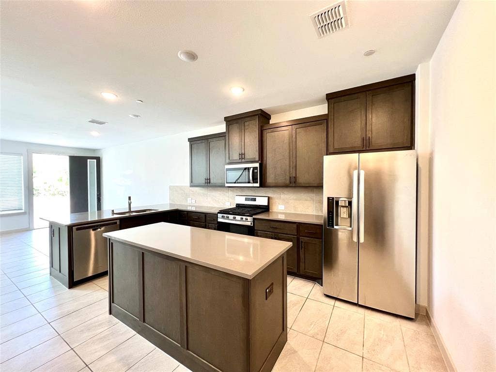 1755 Montgomery Drive, Plano, TX 75075 Kitchen with stainless steel appliances, kitchen peninsula, sink, decorative backsplash, and a kitchen island