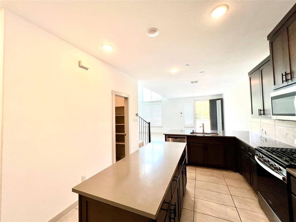 1755 Montgomery Drive, Plano, TX 75075 Kitchen featuring a kitchen island, light tile patterned floors, stainless steel appliances, sink, and kitchen peninsula