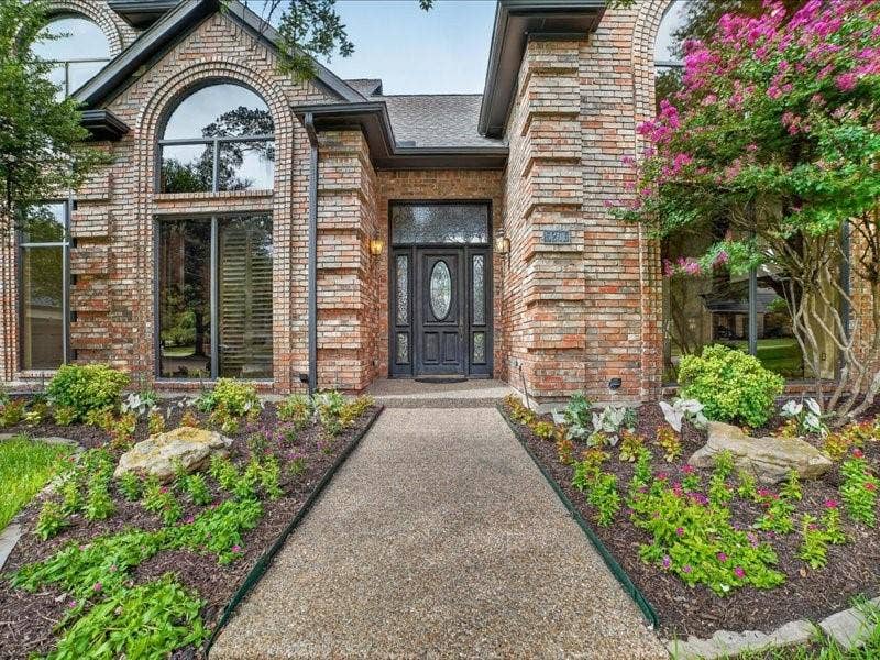 5201 Windjammer Road, Plano, TX 75093 Brick facade residence featuring a covered entry, arched window, transom window, and mature landscaping with a flowering tree