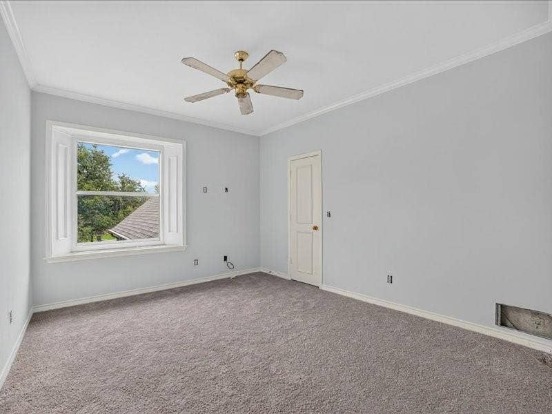 5201 Windjammer Road, Plano, TX 75093 Carpeted room featuring a ceiling fan, crown molding, a window with exterior shutters, a paneled door, and baseboards
