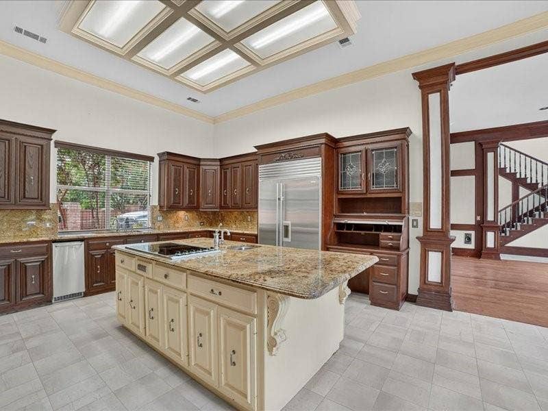 5201 Windjammer Road, Plano, TX 75093 Kitchen featuring rich wood cabinetry, stone countertops, a large center island with integrated cooktop, stainless steel appliances, and a coffered ceiling with recessed lighting