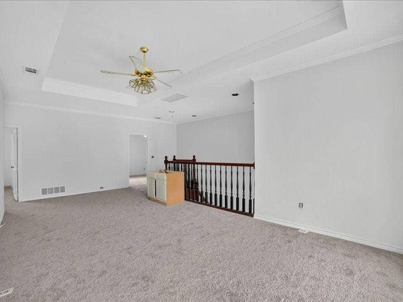 5201 Windjammer Road, Plano, TX 75093 Spacious carpeted room featuring a tray ceiling with crown molding, a decorative ceiling fan, and painted white walls