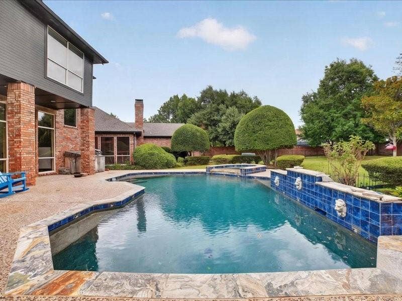 5201 Windjammer Road, Plano, TX 75093 In-ground swimming pool featuring a curved design, blue tile accents, and decorative wall details
