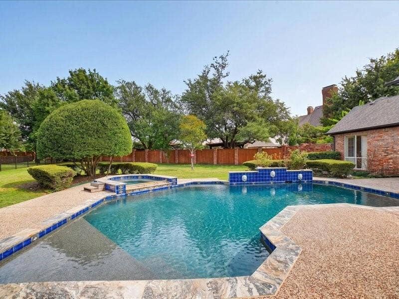 5201 Windjammer Road, Plano, TX 75093 Backyard oasis featuring a swimming pool with blue tile accents, an integrated spa, and a water feature