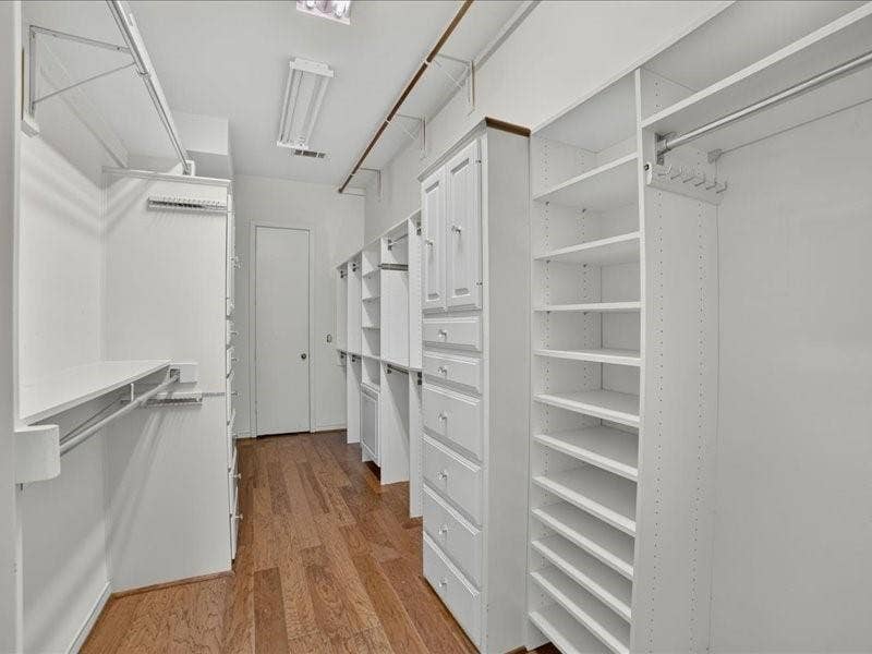 5201 Windjammer Road, Plano, TX 75093 primary bedrrom Walk-in closet featuring built-in white cabinetry, integrated shelving, and wood-finish flooring