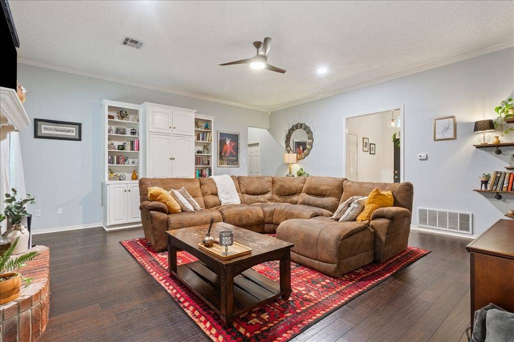 10308 Eagle Mountain Drive, Waco, TX 76712 Spacious living area featuring dark wood-finish flooring, built-in white cabinetry, a white crown molding, and recessed lighting