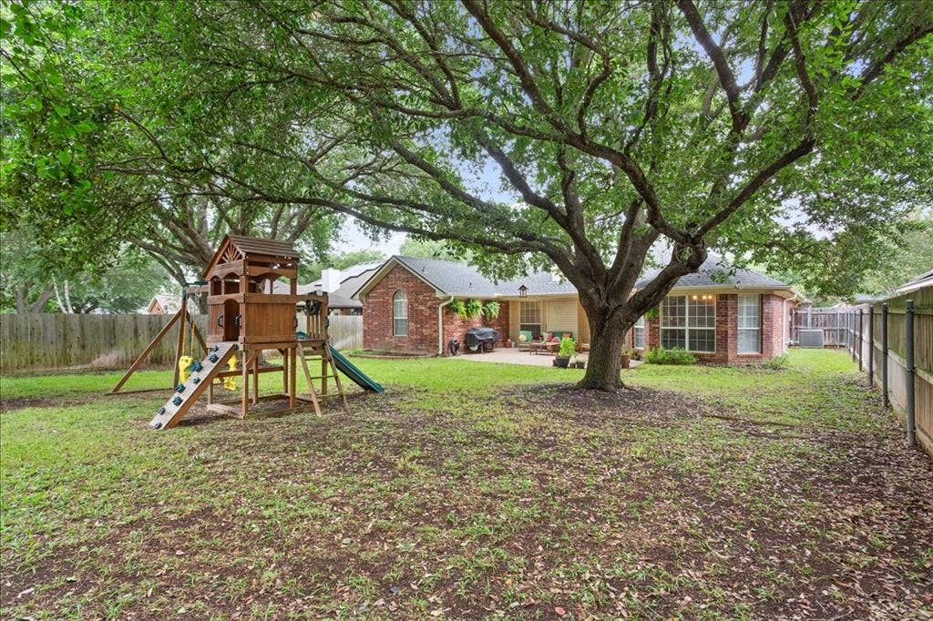 10308 Eagle Mountain Drive, Waco, TX 76712 Expansive fenced backyard featuring a large mature tree providing natural shade, a brick exterior, and a concrete patio